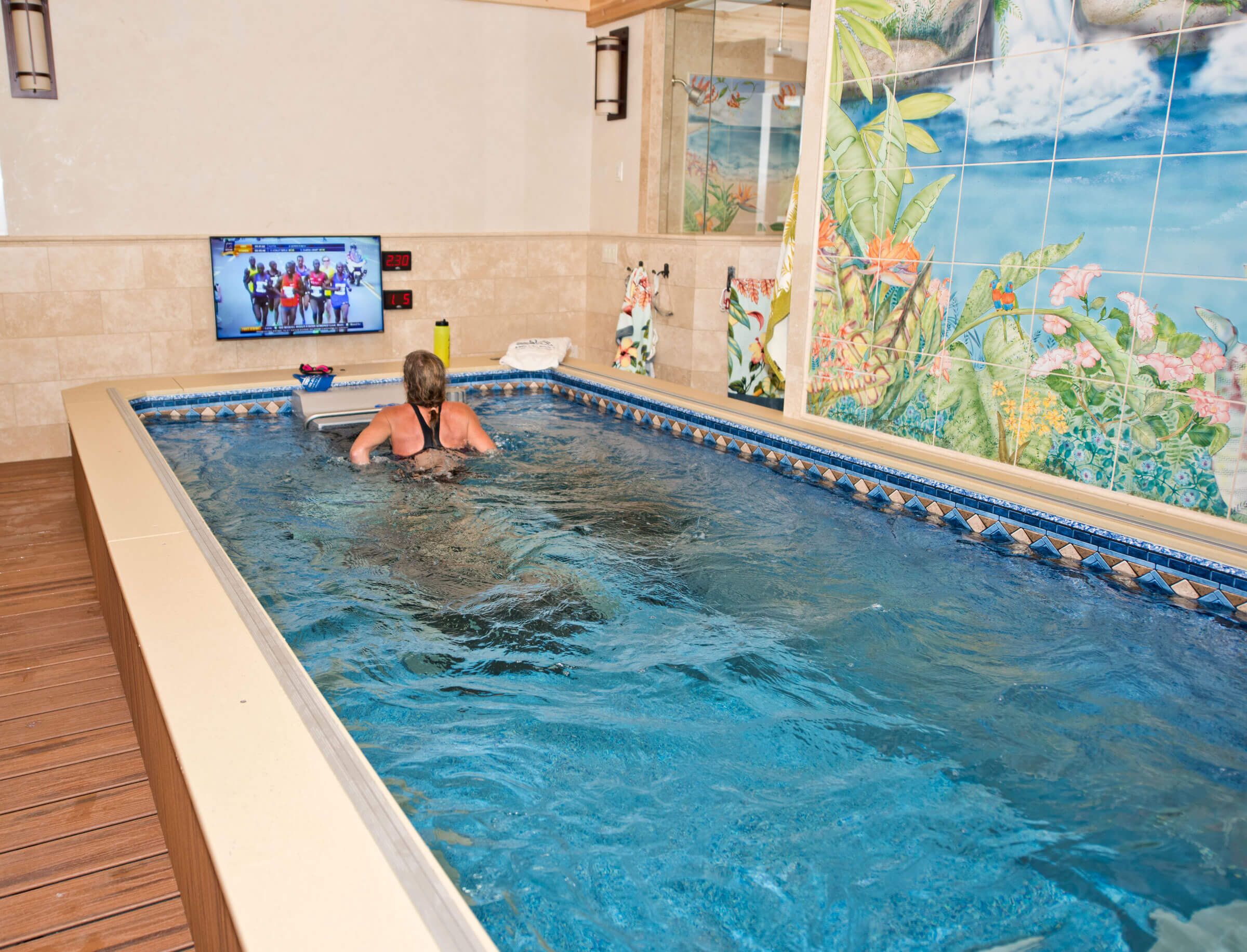 a woman runs on the Underwater Treadmill in her Performance Endless Pool while watching television