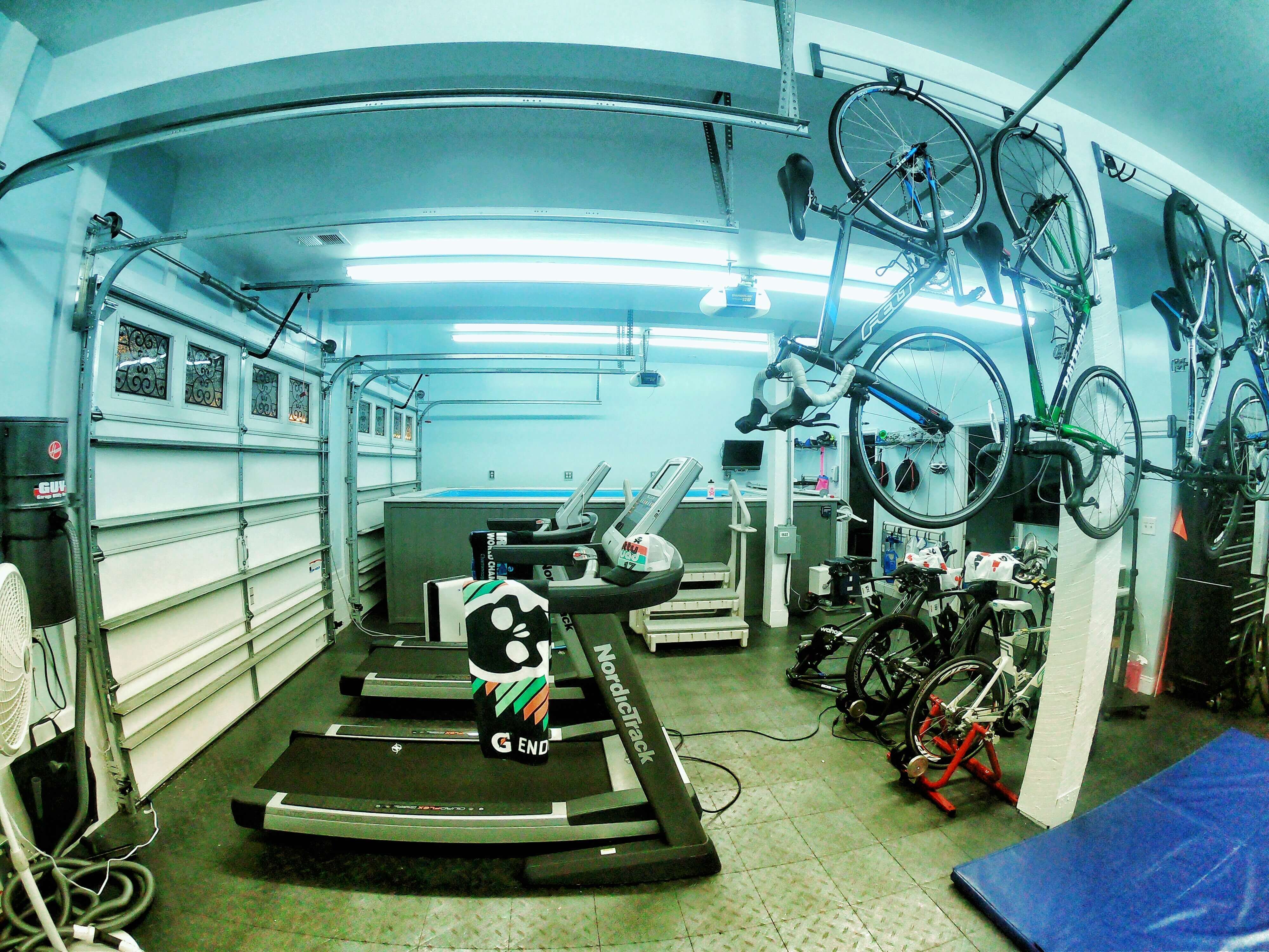 picture of a family's garage 'pain cave' with aboveground Endless Pool, treadmills, and bicycles