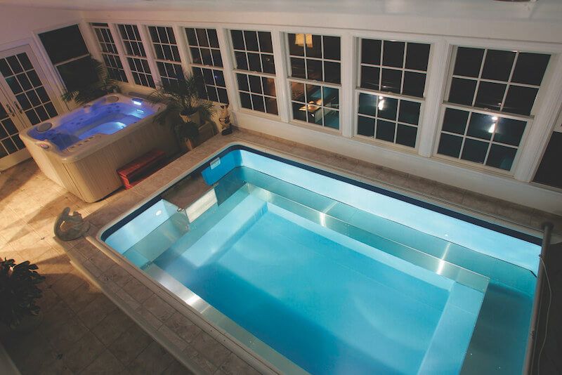 picture of an indoor Endless Pools model in a sunroom at night