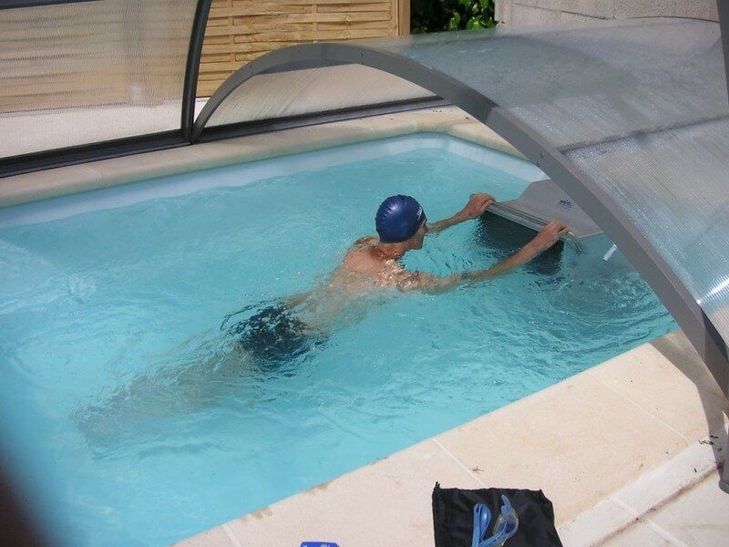picture of swimmer using the Endless Pools current under a retractable pool enclosure