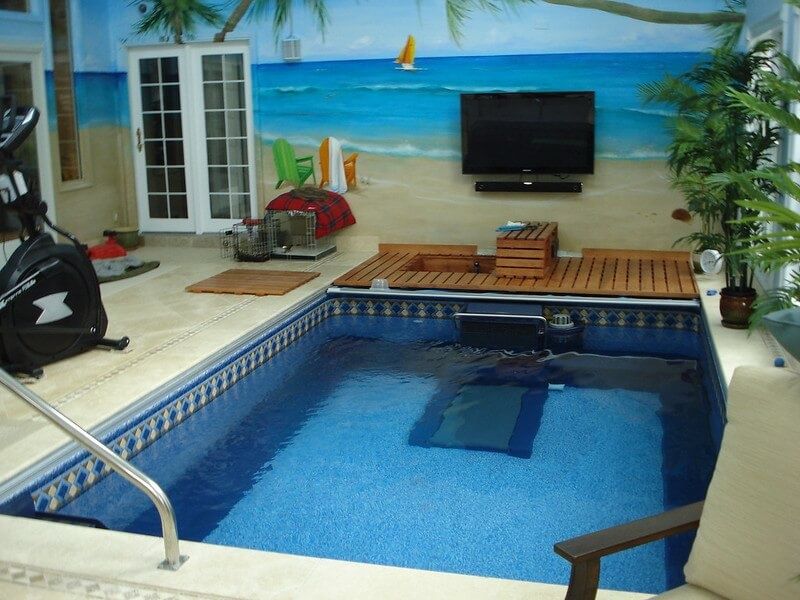 A picture of a garage pool house decorated with beach themed wallpaper and flooring.
