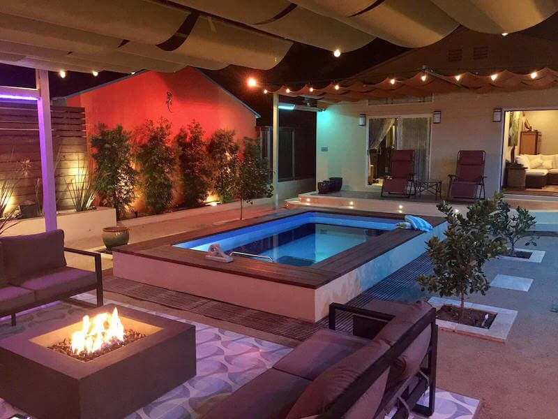 partially in-ground Original Endless Pool with a firepit and decorative lighting