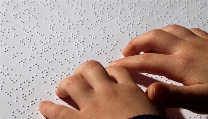 Two hand reading braille on a white background