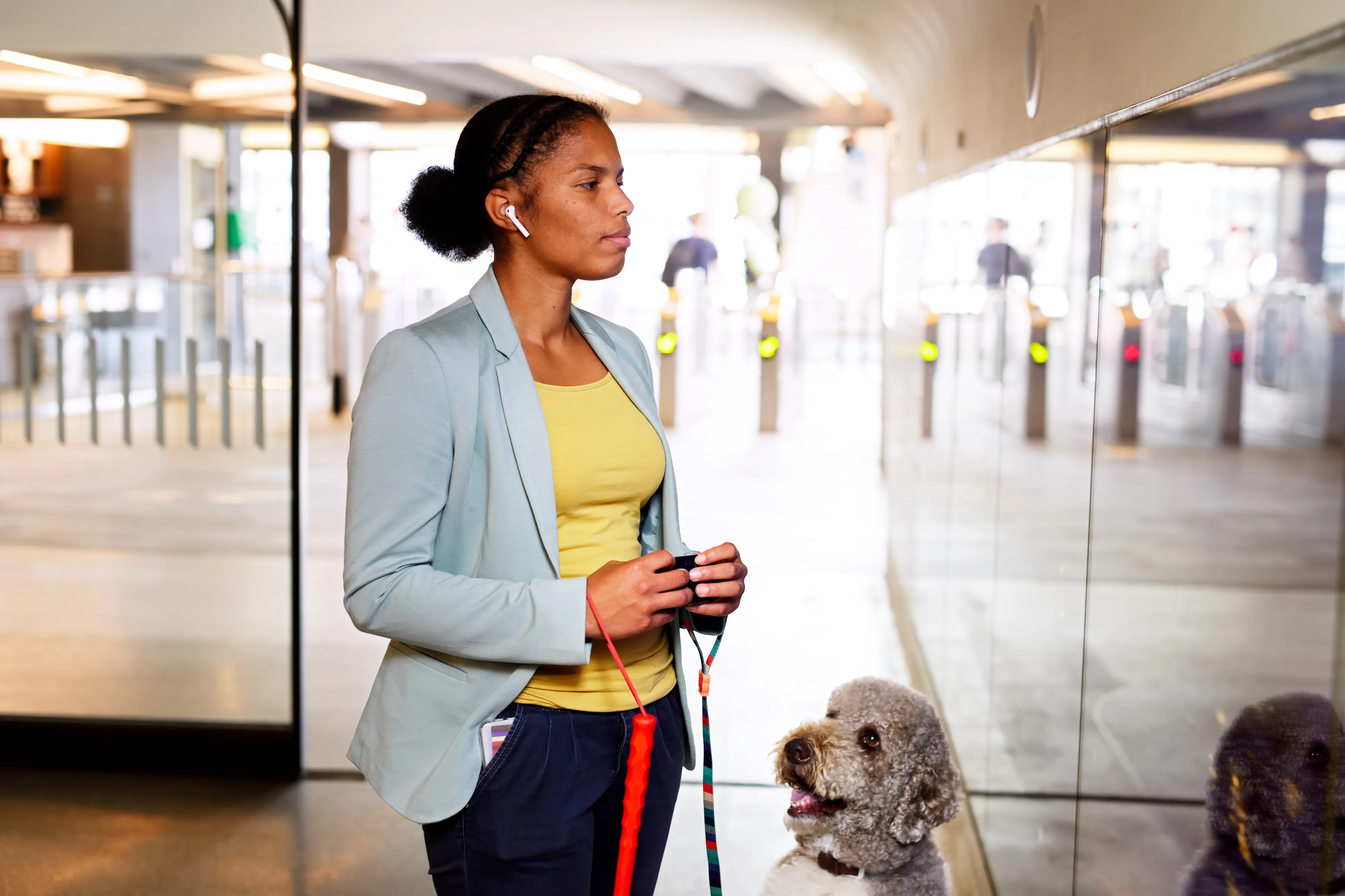 Woman holding a Hable One at the Eindhoven Centraal Train Station. Next to here we have her guide dog that is looking towards her.