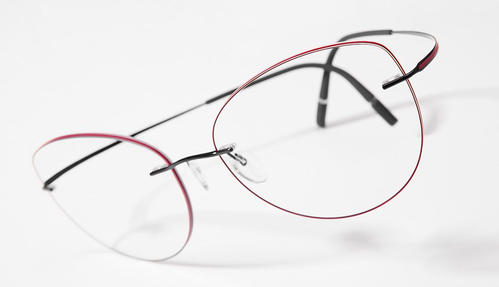 Titan Minimal Art rimless glasses in dark grey and ruby red lens edges floating slightly above the ground