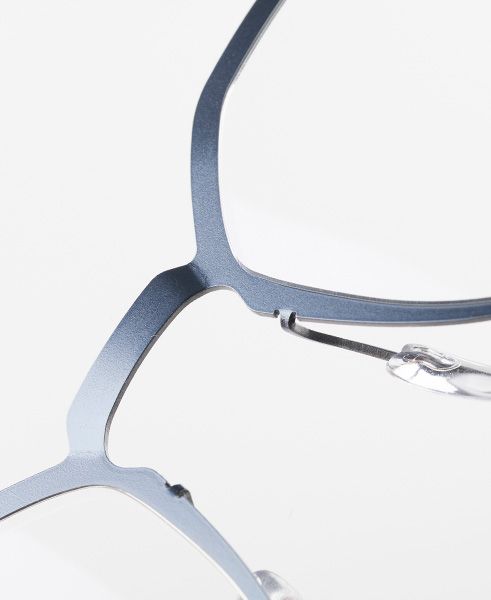 Close-up of Titanium Reframed eyeglasses highlighting the laser-cut titanium full-rim frame, flat sculpted profile, and precise architectural lines in a matte blue finish.