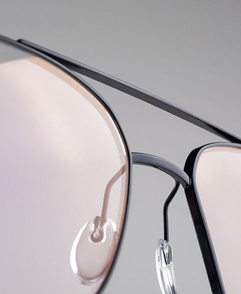 Close-up of the Pure Visionary eyewear frame highlighting the ultra-thin titanium profile wire, angular bridge design, and adjustable transparent nose pads in a sleek dark finish.
