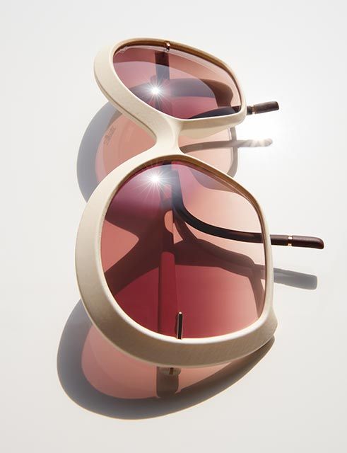 Oversized sunglasses with a sculptural cream-colored frame and warm gradient lenses, shown in a stacked composition with soft shadows, highlighting their bold 70s-inspired design and refined lightness.