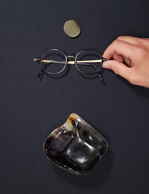 hand holding a horn eyewear model inbetween horn sculptures