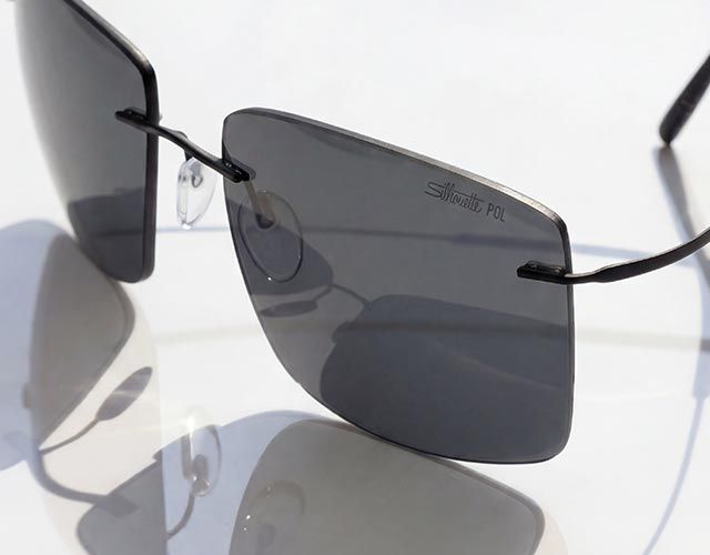 Close de um óculos de sol moderno estilo shield com formato quadrado e lentes degradê, destacando linhas limpas, superfícies suaves e leveza com precisão.