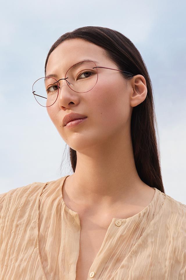 Woman wearing a blouse in rosé tones and rosegold rimless Titan Minimal Art glasses