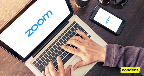 A person's hands typing on a laptop that shows the Zoom logo